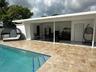 Covered patio featuring stone-tiled flooring, an outdoor kitchen with built-in cabinetry, and a swimming pool with decorative waterline tile and integ