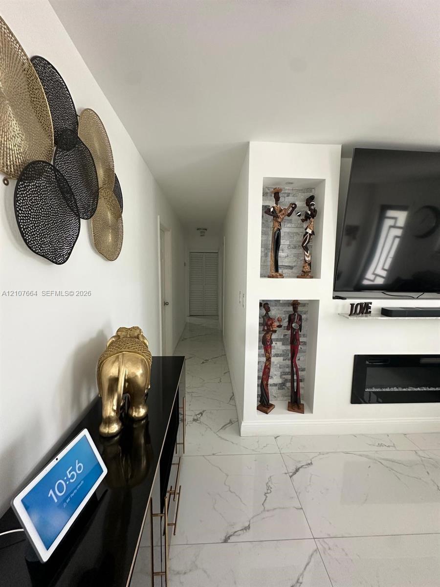 Large-format polished tile flooring featuring a veined pattern, dual built-in wall niches with stone-texture backings, and a sleek linear electric fir