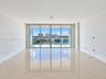 Open-concept room featuring floor-to-ceiling glass sliding doors, polished tile flooring, and a private balcony with a glass railing
