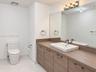 Floating wood-finish double vanity with rectangular vessel sinks, soaking tub, glass-enclosed walk-in shower with stone tile flooring, and large-forma