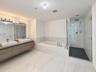 Interior hallway featuring light-toned tile flooring, white walls, flush-mount ceiling lighting, and louvered closet doors