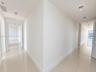 Room interior featuring polished tile flooring, neutral walls, ceiling-mounted lighting, and oversized windows with roller shades