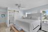 Sliding barn door with brass-tone hardware, wood-finish flooring, ceiling fan, and multi-pane windows with horizontal blinds
