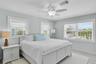 Bedroom featuring neutral wall paint, white wood-finish flooring, three windows with horizontal blinds, and a central ceiling fan with an integrated l