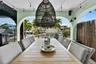 Covered outdoor living space featuring arched structural openings, built-in stainless steel grill, woven pendant light fixture, and mounted exterior w