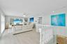 Open-concept room featuring wood-finish flooring, white traditional balustrade railing, track lighting, and ceiling fan