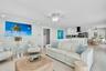 Open-concept interior featuring wood-finish flooring, white cabinetry, track lighting, ceiling fans, and balustrade railing