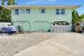 Two-story residence featuring architectural arched structural supports, a decorative metal privacy gate, concrete driveway, and low-maintenance gravel