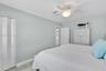 Light-toned wood-finish flooring, white bifold closet doors, six-panel interior door, and a ceiling fan with integrated light fixture