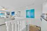White balustrade railing, track lighting, ceiling fan with integrated light fixture, and light-toned tile flooring