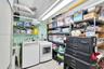 Utility room featuring a dedicated laundry station, wall-mounted utility sink, overhead fluorescent lighting, and open shelving
