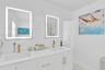 Dual-sink vanity featuring integrated rectangular basins, white stone-finish countertop, and gold-toned hardware, complemented by two rectangular LED-