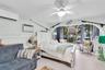 Light-toned wood-finish flooring, wall-mounted mini-split HVAC unit, ceiling fan with integrated lighting, and an arched glass entryway