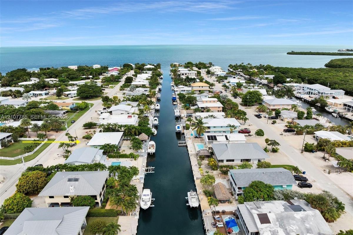 Aerial perspective of a canalfront property featuring direct water access, a private boat slip, and proximity to open bay waters