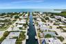 Aerial perspective of a canalfront property featuring direct water access, a private boat slip, and proximity to open bay waters
