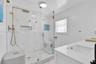 Walk-in shower with gold-tone hardware, a built-in recessed niche, stone-finish wall tile, a hexagonal tile floor, and a frameless glass enclosure