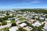 Aerial perspective of a coastal residential neighborhood featuring expansive water, proximity to protected natural areas, palm-dotted landscaping, and