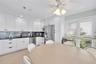 Kitchen featuring white shaker-style cabinetry, dark stone countertops, blue glass tile backsplash, stainless steel appliances, and wood-finish floori