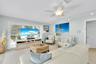 Living area featuring light-toned wood-finish flooring, recessed track lighting, a ceiling fan with integrated light fixture, and windows equipped wit