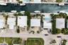 Aerial view of a waterfront property featuring a private boat dock, rectangular swimming pool with stone decking, and mature palm landscaping
