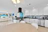 Kitchen featuring white cabinetry, dark countertops, a textured tile backsplash, a stainless steel dishwasher, and a matte black wall-mounted range ho