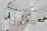 Room featuring wood-finish flooring, a sliding white barn door, a recessed wall niche with glass shelving, a multi-paneled door, and an attached ceili