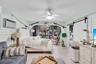 Archway opening with wood-finish flooring, board-and-batten wall detailing, sliding barn door, and ceiling-mounted fan with integrated lighting