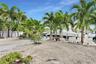 Waterfront exterior featuring a gravel landscape, mature palm trees, concrete walkway, and private boat dock
