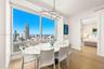 Floor-to-ceiling windows, wood-finish flooring, linear modern chandelier, and neutral wall palette