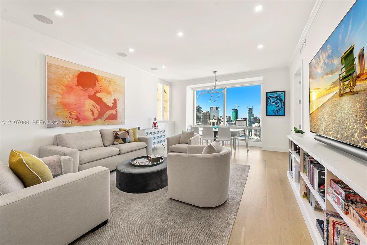 Living space featuring white-oak engineered wood flooring, recessed lighting, integrated ceiling speakers, built-in shelving, and floor-to-ceiling win