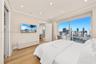 Floor-to-ceiling windows with urban skyline scenery, wood-finish flooring, recessed ceiling lighting, and crown molding