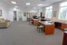Open-concept workspace featuring carpeted flooring, large multi-pane windows, recessed ceiling lighting, and neutral wall tones