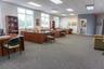 Open-plan interior featuring carpeted flooring, drop ceiling with recessed lighting, and large windows