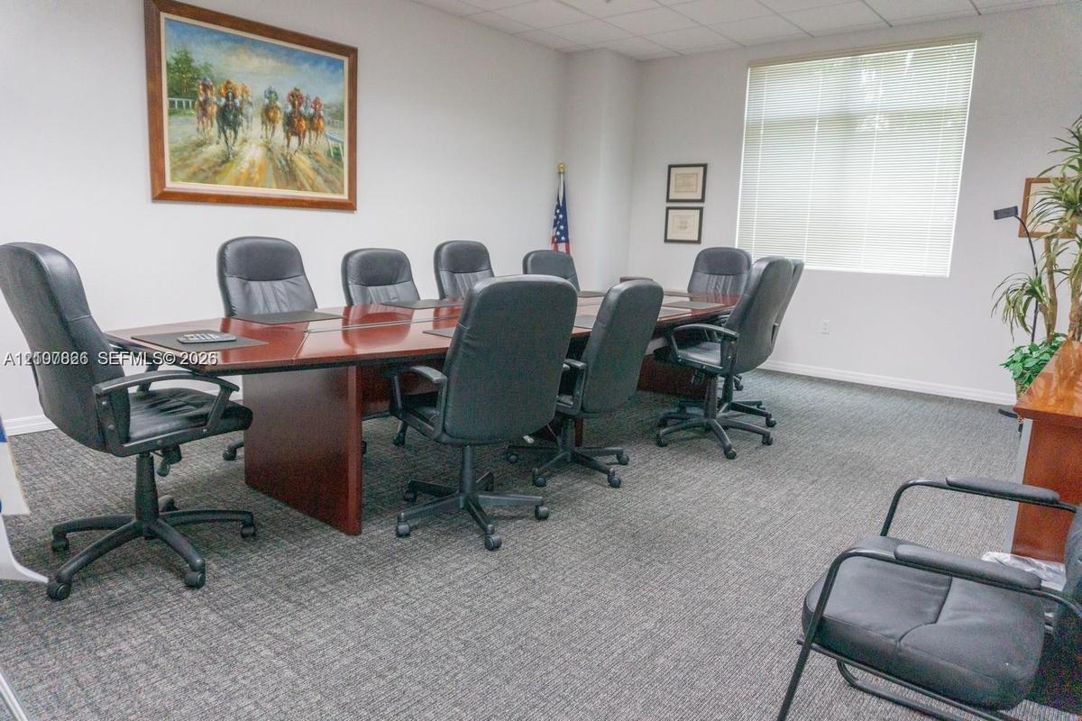 Conference room featuring neutral wall finishes, integrated drop-ceiling lighting, carpeting, and a large window with blind installation
