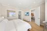 Neutral-toned interior featuring recessed lighting, wood-finish flooring, custom built-in closet cabinetry, and a large horizontal window