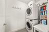 Laundry area featuring a stacked washer and dryer, built-in open shelving, and a wall-mounted hook rack