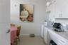 Kitchen area featuring white upper and lower cabinetry, laminate countertops, a stainless steel sink with a goose-neck faucet, and tile flooring