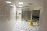 Restroom featuring floor-to-ceiling neutral wall tile, square-patterned tile flooring with dark inlays, stainless steel partitions, and a dark-toned v