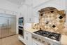 The chef's kitchen features hi-end appliances that includes a 6-burner gas cooktop, oversized built-in refrigerator, built-in ovens and warming drawer
