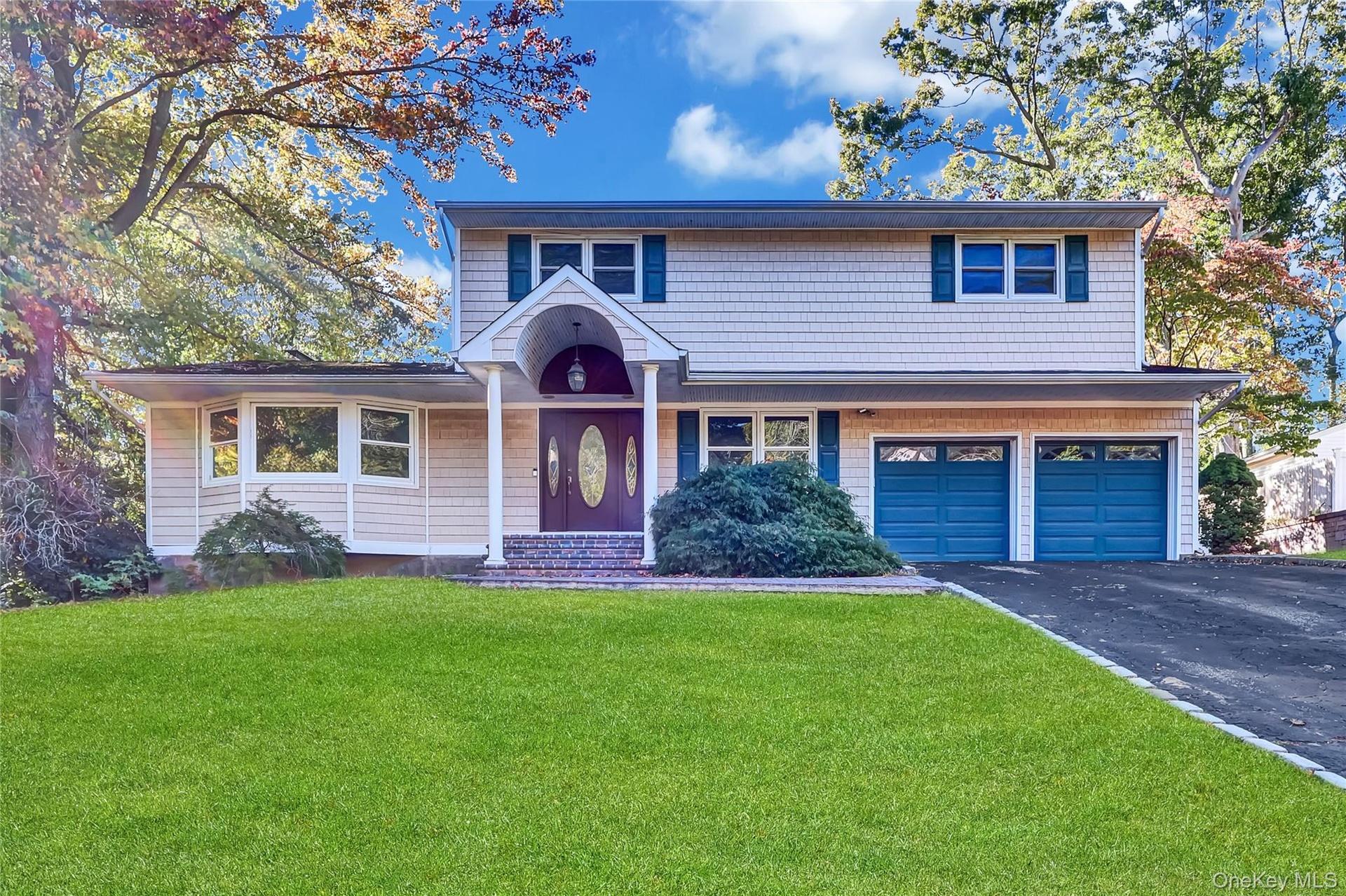 Two-story exterior featuring shake-style siding, a covered arched entryway, a double-car garage, and multi-pane windows with decorative shutters