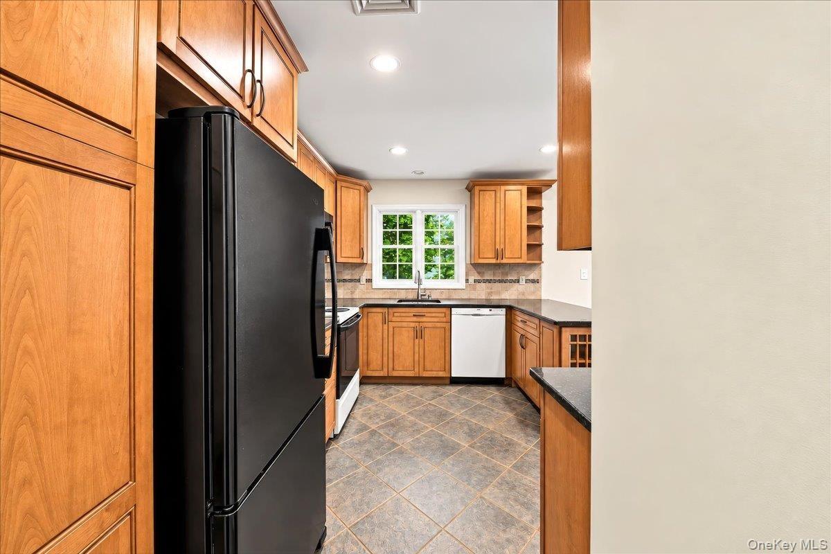 Updated kitchen featuring warm wood cabinetry, a ceramic tile backsplash, and ceramic tile flooring, with beautiful Hudson River views from the window