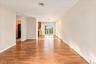 Bright living room with newly refinished hardwood floors flowing seamlessly into the dining room and kitchen, offering beautiful river views.