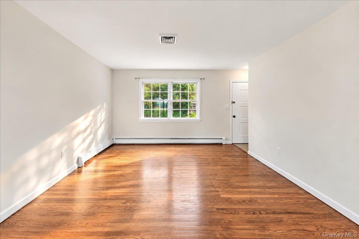 Welcoming entryway opens to a bright, inviting living room featuring beautifully refinished hardwood floors.