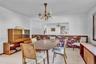 Dining area featuring an exposed brick accent wall, a large rectangular wall cutout, and a traditional multi-arm chandelier