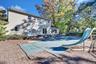 Exterior view of the residence featuring horizontal siding, a multi-level stone paver patio, an in-ground pool with a slide, and mature trees