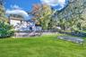 Backyard featuring a manicured lawn, fenced swimming pool with a slide, and a sand area
