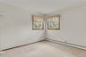 Neutral-toned interior featuring dual windows with wood trim and wall-to-wall carpeting