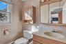 Bathroom featuring wood-finish cabinetry, a built-in medicine cabinet with integrated lighting, a single-basin vanity, and a window with a valance