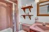 Walk-in shower with metal-framed glass enclosure, pink tile surround, integrated pink vanity with basin, wooden medicine cabinet, and wall-mounted woo