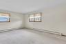 Neutral interior room featuring wall-to-wall carpeting and dual windows with wood-trimmed frames